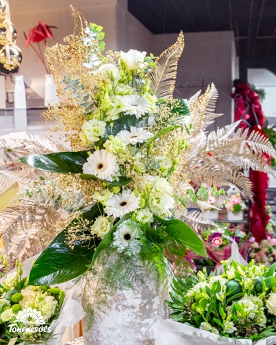 Composition florale Nouvel An blanche et verte avec fleurs blanches, feuillages et touches dorées élégantes.